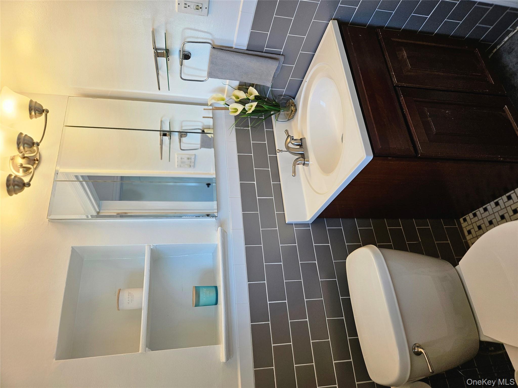79-31 211th Street Queens, NY 11364 - Photo 27 of 28 Bathroom featuring tile walls, vanity, toilet, and wainscoting