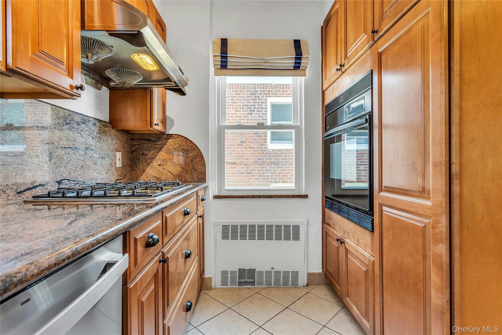 79-31 211th Street Queens, NY 11364 - Photo 10 of 28 Kitchen with range hood, radiator heating unit, appliances with stainless steel finishes, decorative backsplash, and cabinetry