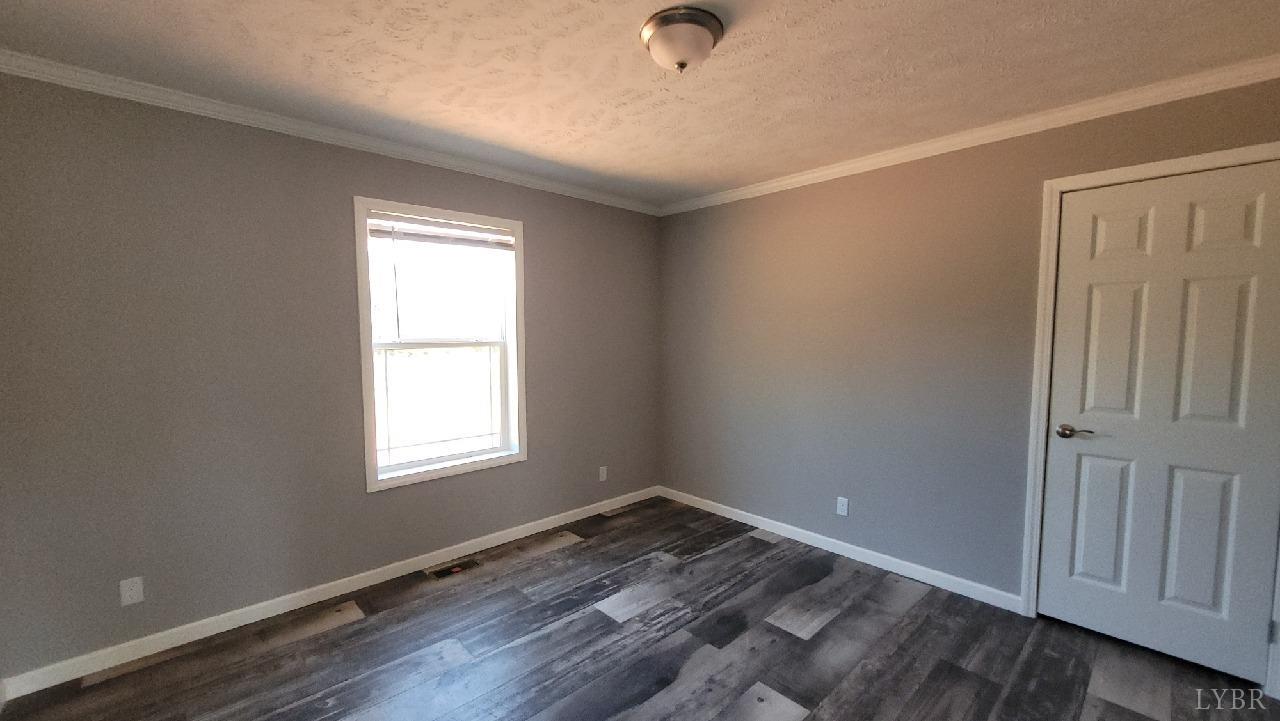 414 Loman Road Meherrin, VA 23954 - Photo 8 of 16 an empty room with wooden floor cabinet and windows
