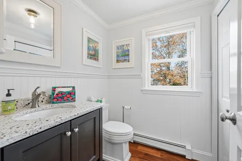 a bathroom with a granite countertop sink a toilet and a window