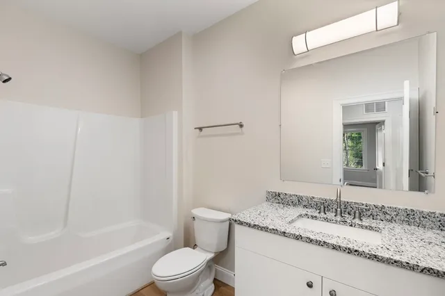 a bathroom with a granite countertop sink a toilet and bathtub