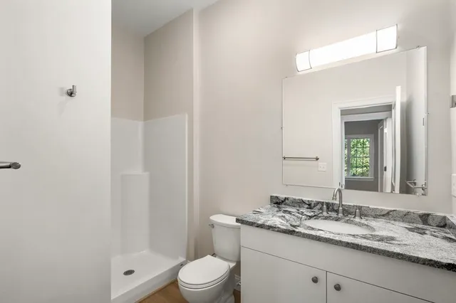 a bathroom with a granite countertop sink a toilet and shower