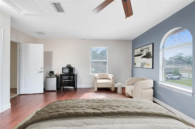 a spacious bedroom with a bed and wooden floor