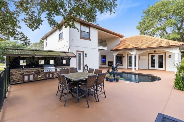 a view of a patio with table and chairs with a barbeque and a trees