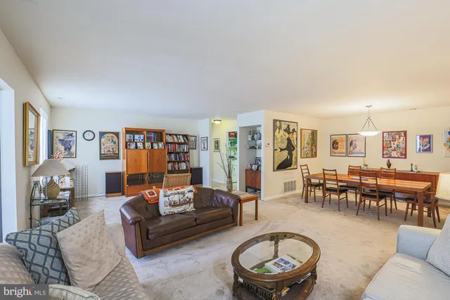 a living room with furniture and a dining table with bookshelf