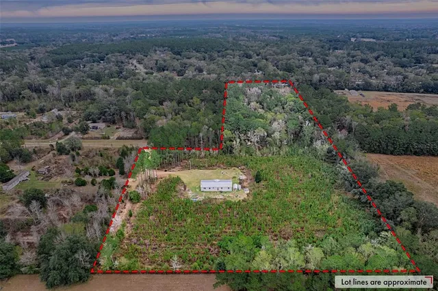 an aerial view of residential house with outdoor space and trees all around