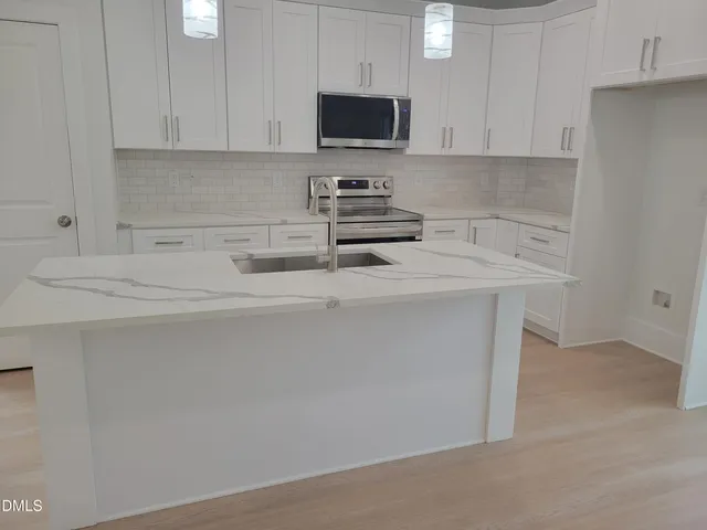 a kitchen with stainless steel appliances granite countertop a sink stove and microwave