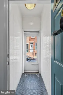 a view of a hallway to a livingroom with wooden floor and a refrigerator