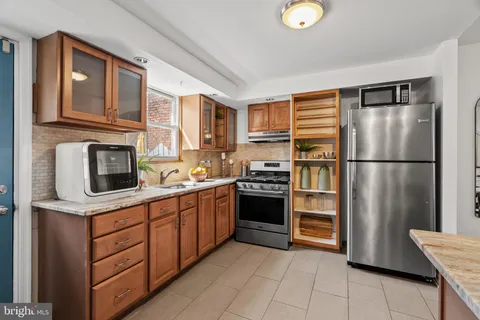 a kitchen with stainless steel appliances granite countertop a refrigerator a stove and a sink