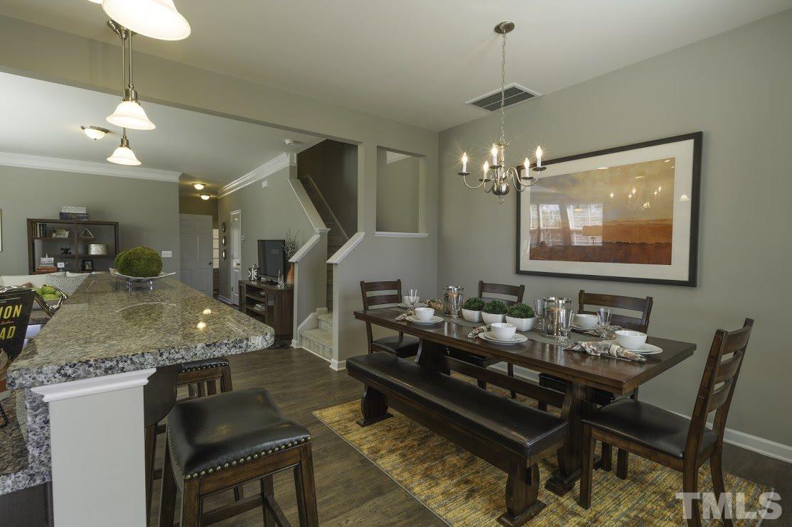 1418 Chatuga Way Raleigh, NC 27610 - Photo 3 of 13 a dining room with wooden floor a chandelier a wooden table and chairs