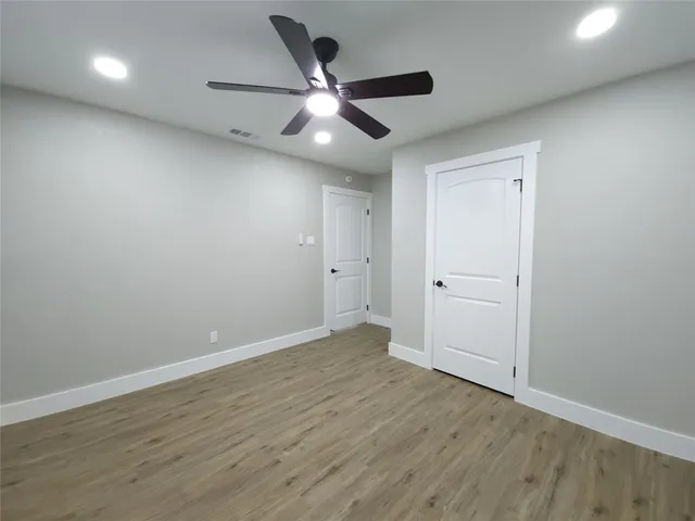 an empty room with wooden floor and ceiling fan