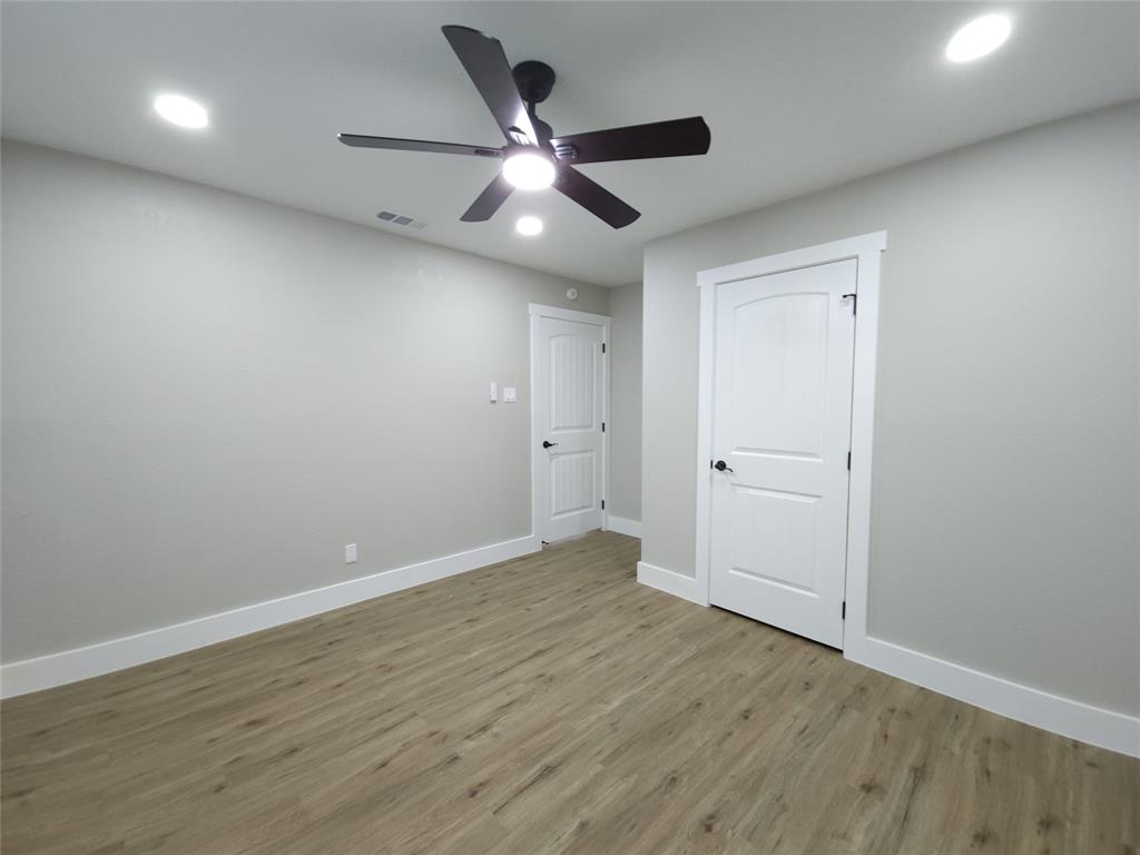 7039 Bates Street Dallas, TX 75227 - Photo 21 of 40 an empty room with wooden floor and ceiling fan