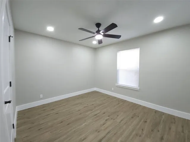 an empty room with wooden floor ceiling fan and window