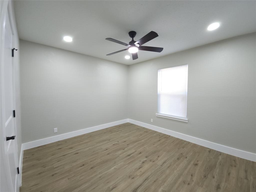 7039 Bates Street Dallas, TX 75227 - Photo 22 of 40 an empty room with wooden floor ceiling fan and window