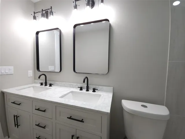 a bathroom with 2 sink toilet and mirror