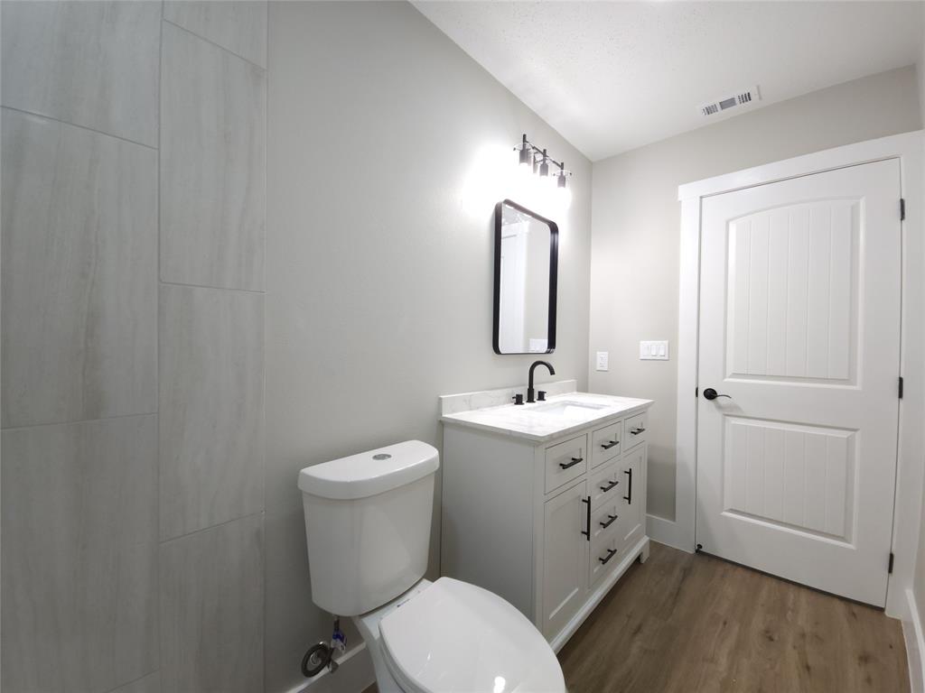 7039 Bates Street Dallas, TX 75227 - Photo 34 of 40 a bathroom with a toilet a sink and mirror