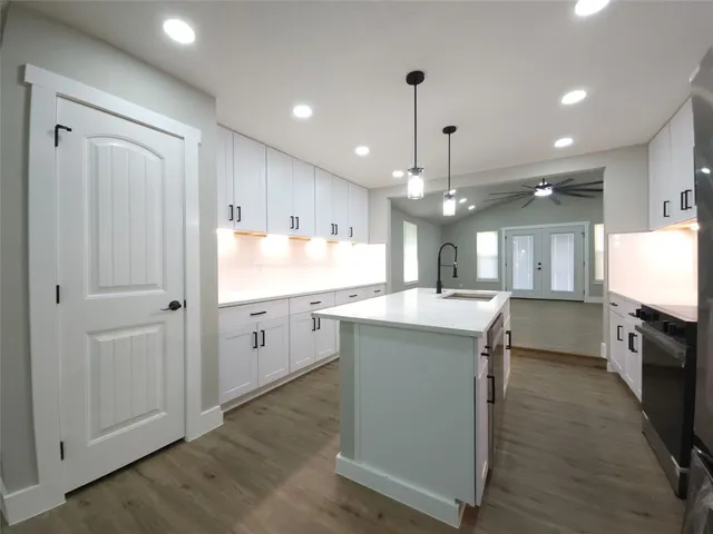 a kitchen with stainless steel appliances granite countertop refrigerator a sink dishwasher a oven and white cabinets with wooden floor