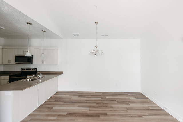 4653 South Alder Drive, Unit H304 Mapleton, UT 84664 - Photo 4 of 14 Kitchen featuring a peninsula, stainless steel appliances, light wood-type flooring, and suspended lighting
