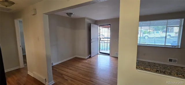 a view of an empty room with wooden floor and a window