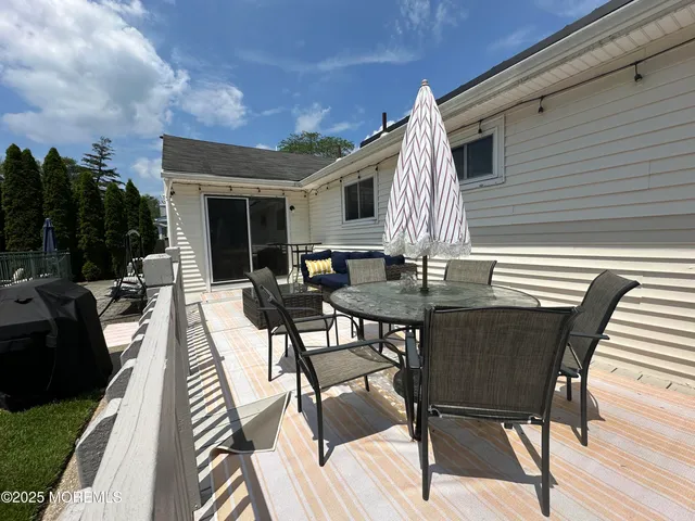 a view of a backyard with table and chairs potted plants and large tree