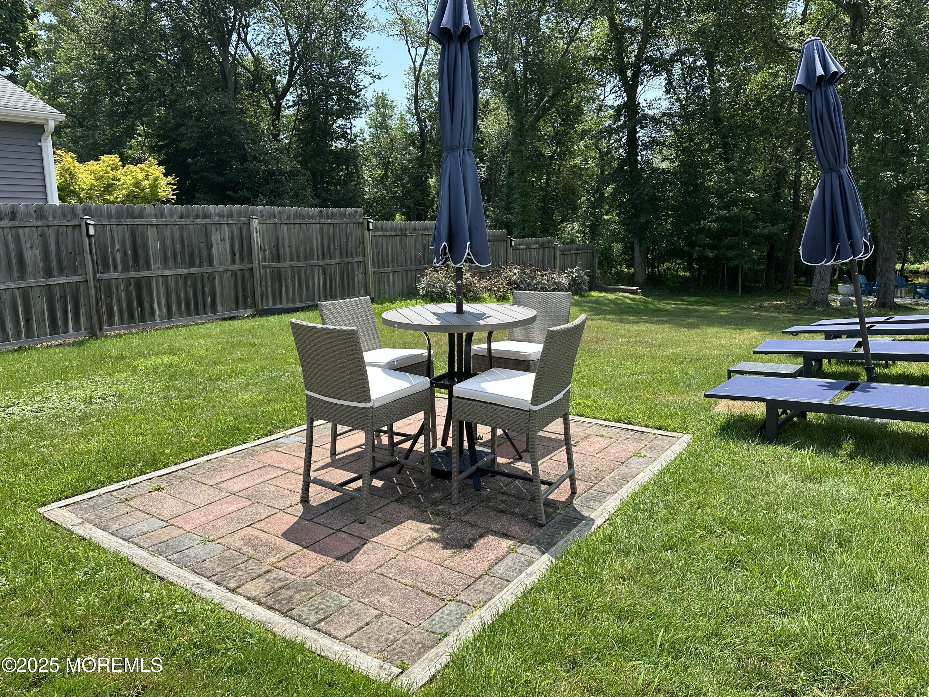 1007 Shore Road Spring Lake Heights, NJ 07762 - Photo 40 of 53 a view of a backyard with table and chairs potted plants and wooden fence