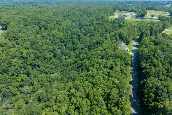an aerial view of residential house with outdoor space and trees all around