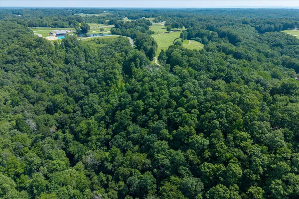 an aerial view of a house with outdoor space and trees all around