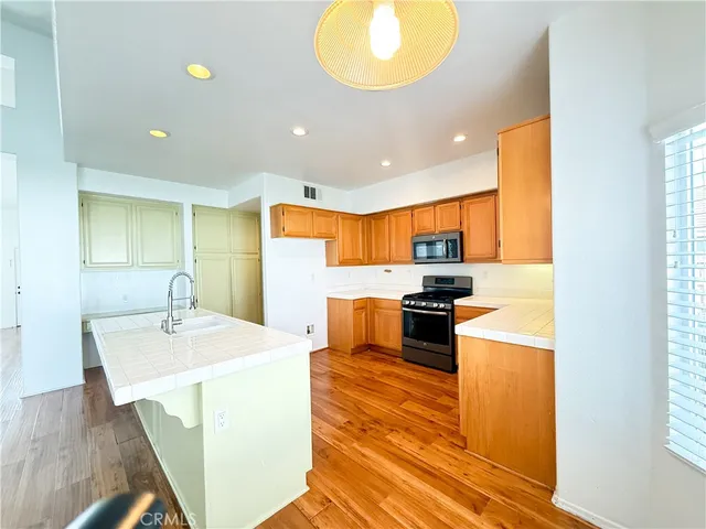 a kitchen with stainless steel appliances granite countertop a sink a stove top oven a counter space and cabinets