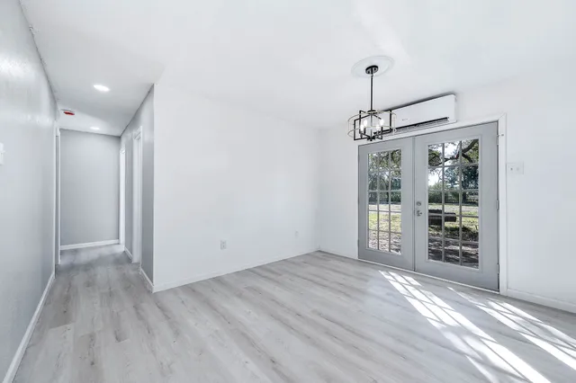 a view of an empty room with window and wooden floor