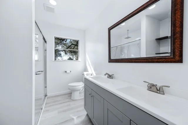 a bathroom with a double vanity sink mirror and toilet