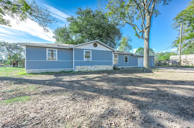 a view of a house with a yard and large tree