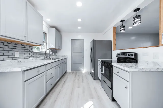a kitchen with a sink stove cabinets and refrigerator