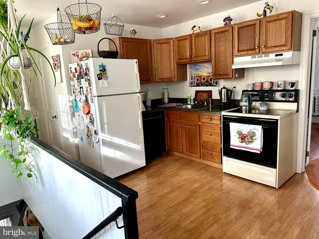 a kitchen with stainless steel appliances granite countertop a refrigerator a stove top oven a sink and dishwasher with wooden floor