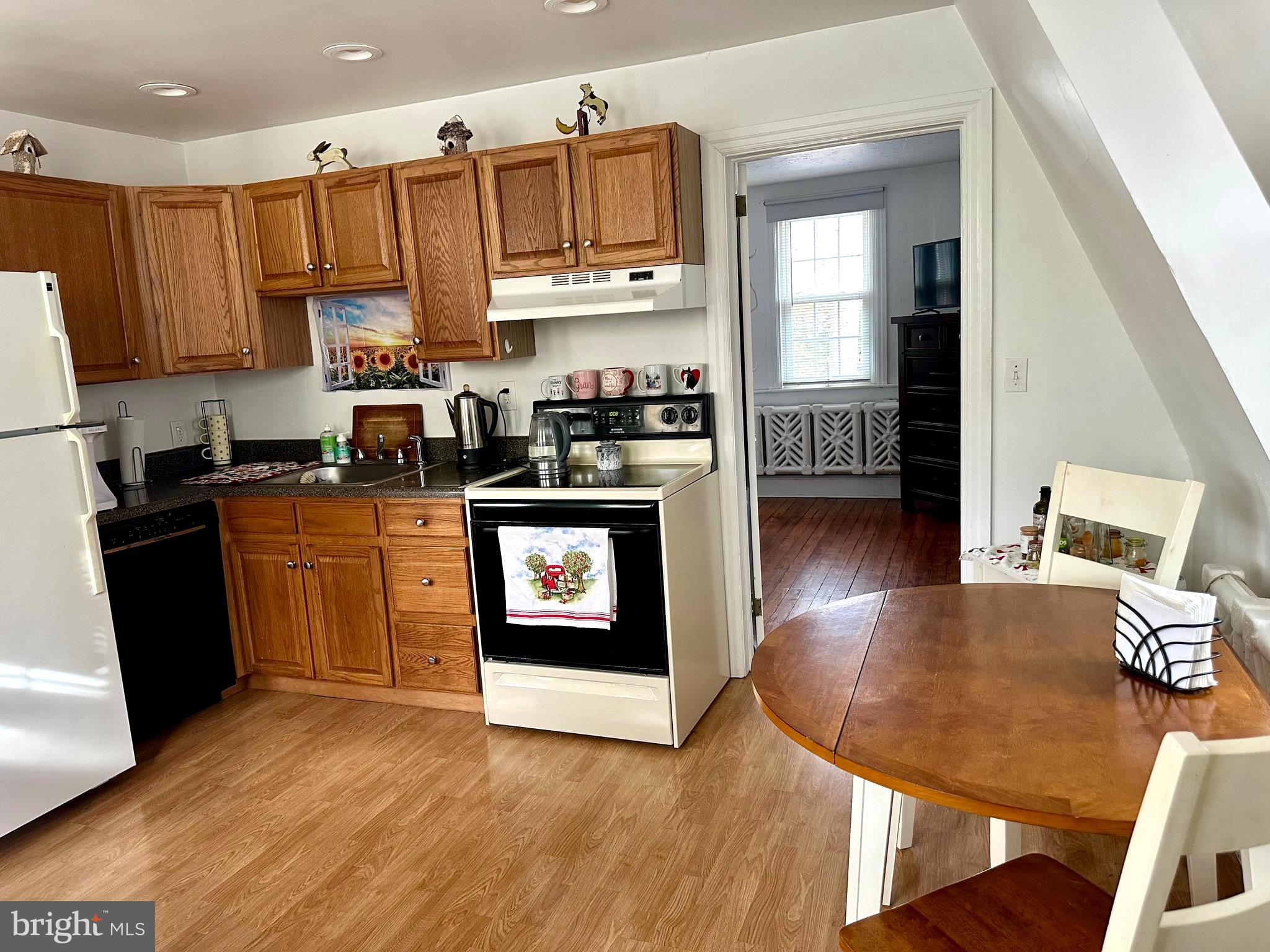 1 West Street, Unit 414 Media, PA 19063 - Photo 15 of 20 a kitchen with stainless steel appliances granite countertop a refrigerator a stove top oven a sink and dishwasher with wooden floor