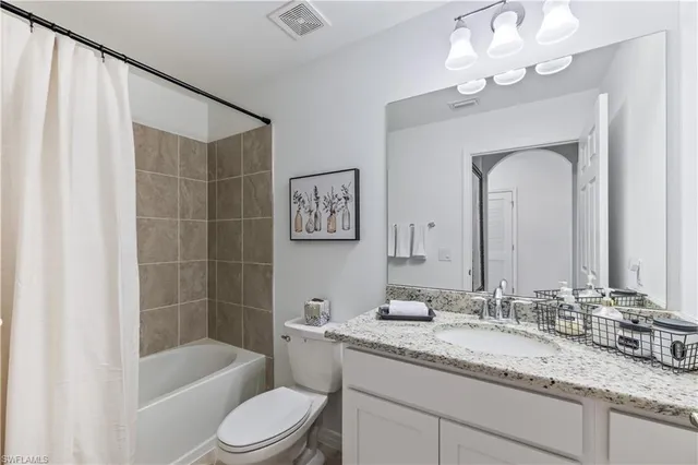 a bathroom with a granite countertop sink a toilet and bathtub