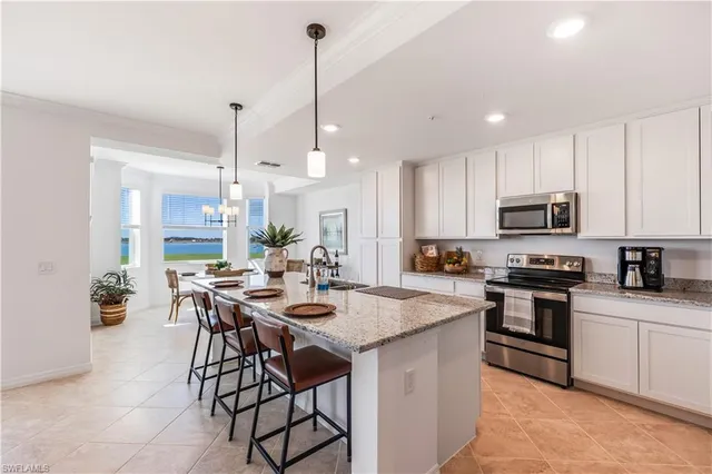 a kitchen with stainless steel appliances kitchen island granite countertop a stove a sink a microwave a dining table and chairs