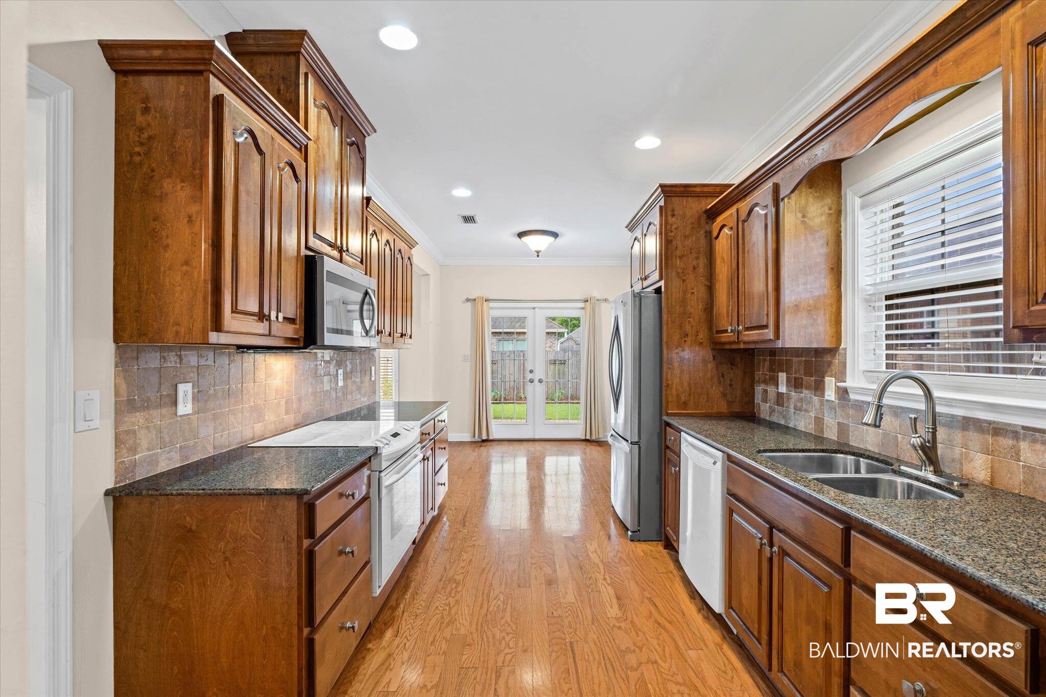 1003 Weatherby Street South Saraland, AL 36571 - Photo 15 of 31 Kitchen with french doors, wood finish cabinetry, dark stone counters, stainless steel appliances, and light wood-type flooring