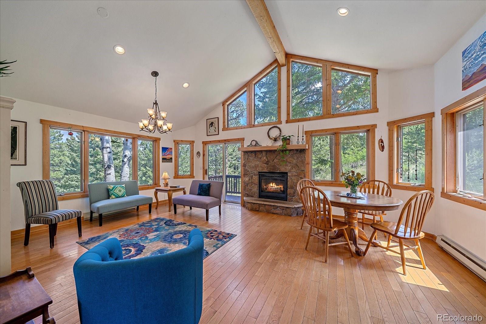 14482 Jubilee Trail Pine, CO 80470 - Photo 14 of 40 a living room with furniture a fireplace and a floor to ceiling window