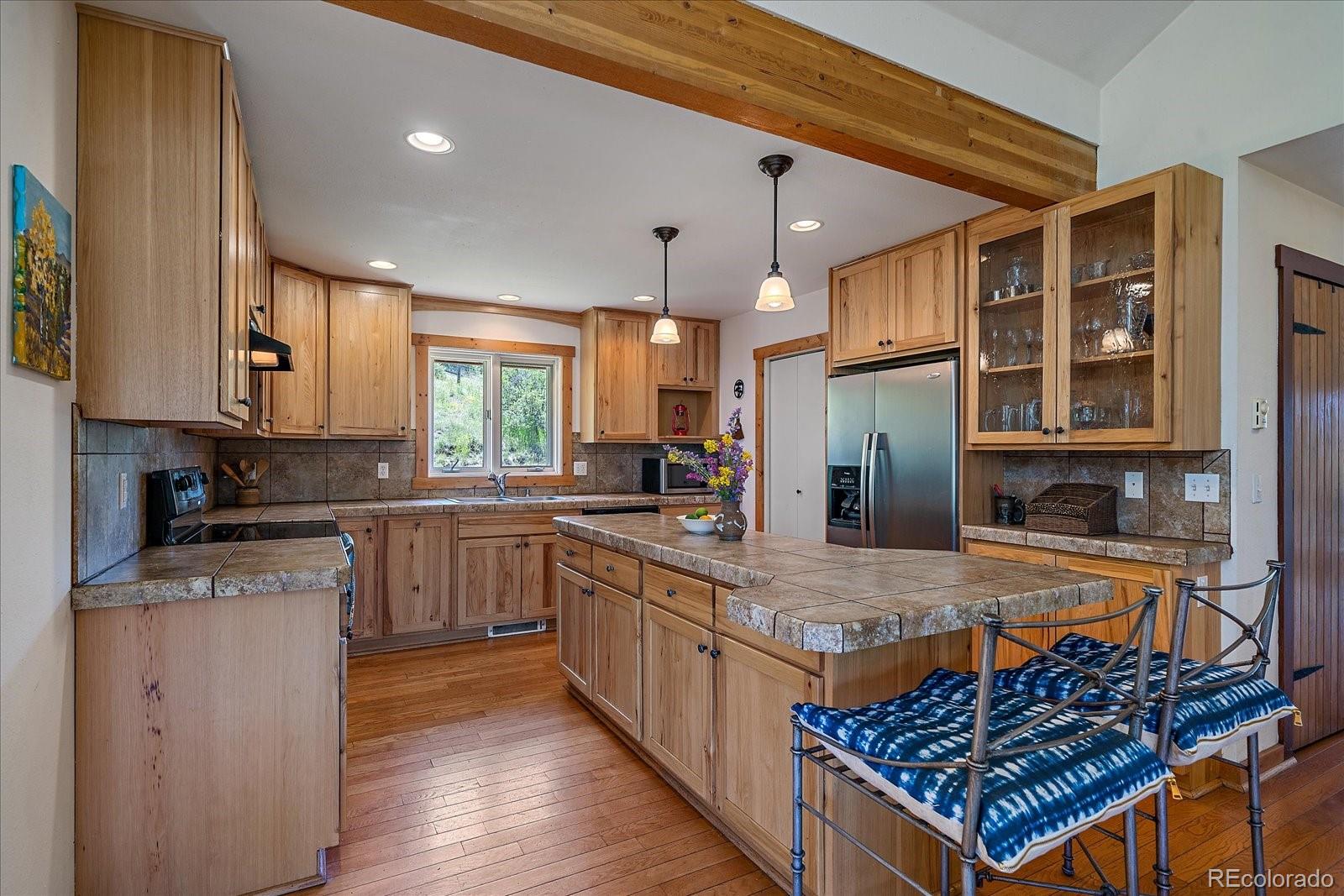 14482 Jubilee Trail Pine, CO 80470 - Photo 19 of 40 a kitchen with stainless steel appliances granite countertop a stove top oven a sink dishwasher and cabinets with wooden floor