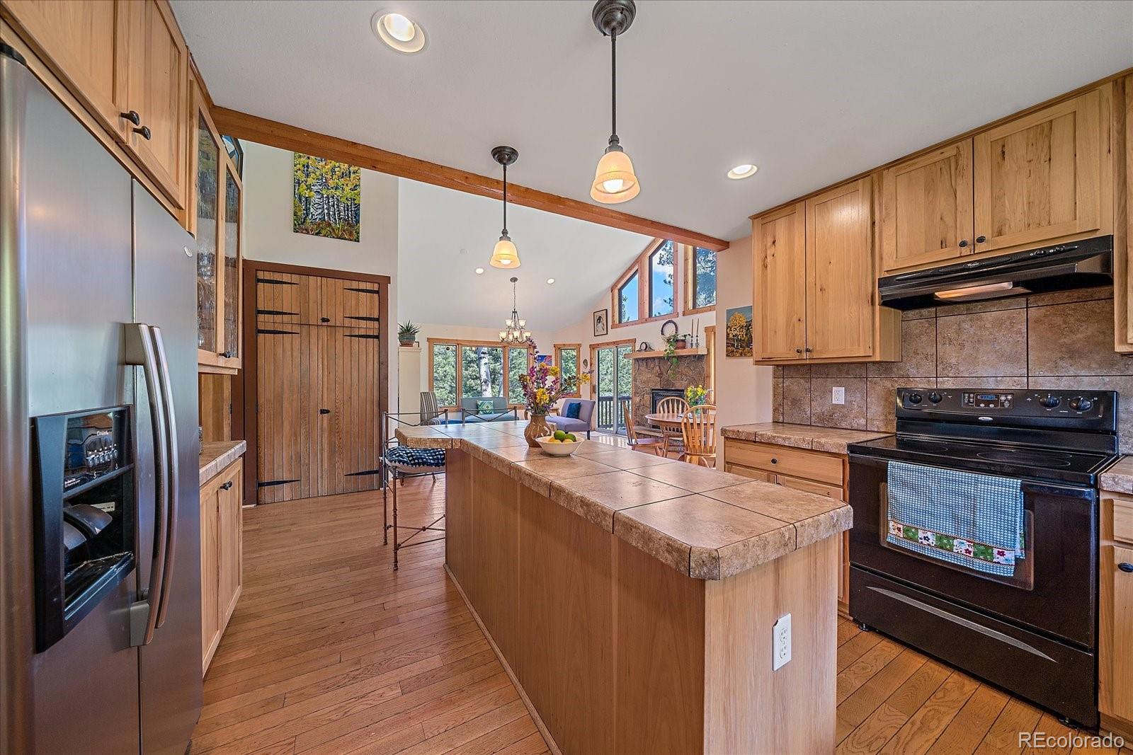 14482 Jubilee Trail Pine, CO 80470 - Photo 22 of 40 a kitchen with stainless steel appliances granite countertop a refrigerator a stove and a wooden floors