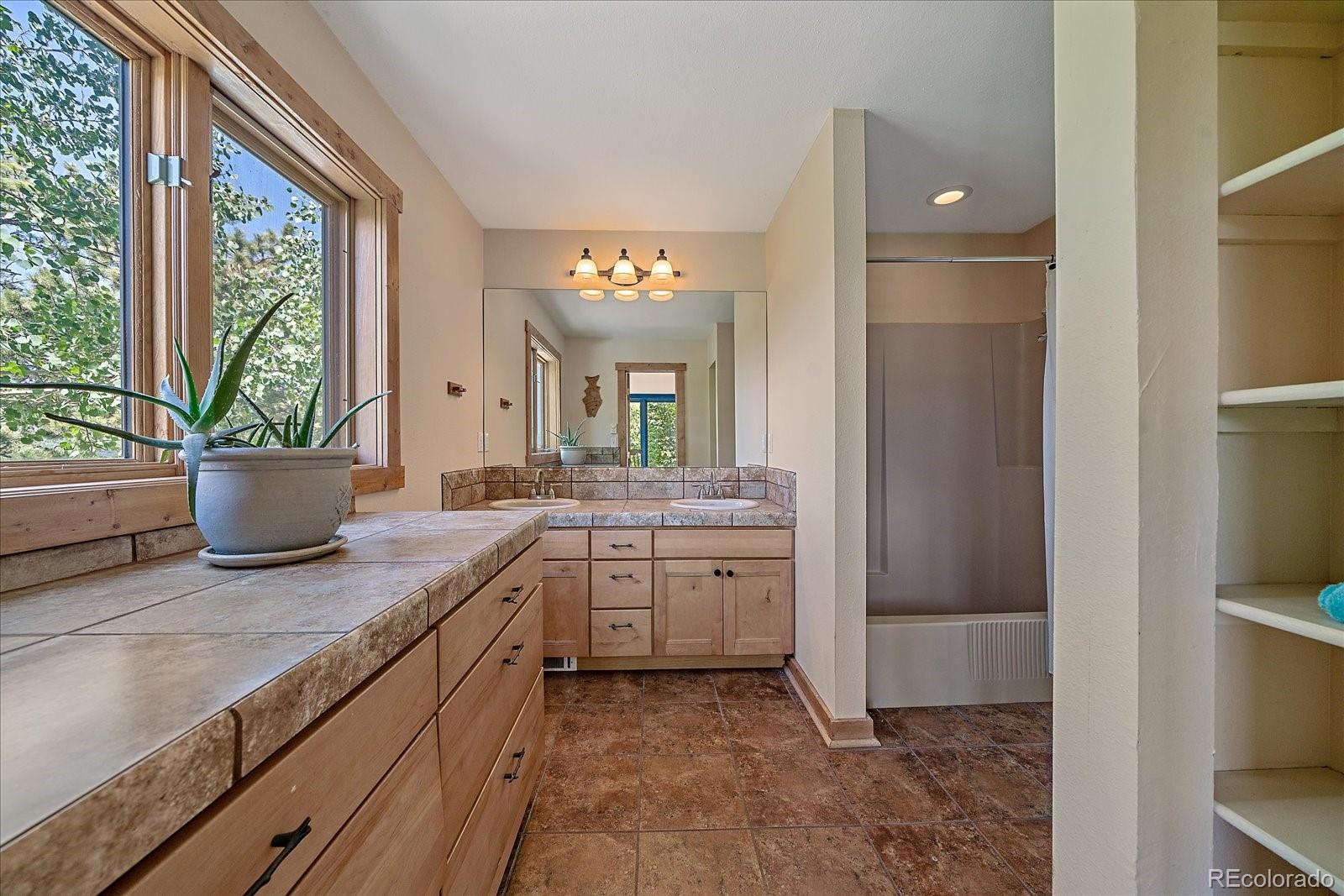 14482 Jubilee Trail Pine, CO 80470 - Photo 28 of 40 a spacious bathroom with a granite countertop sink and a mirror