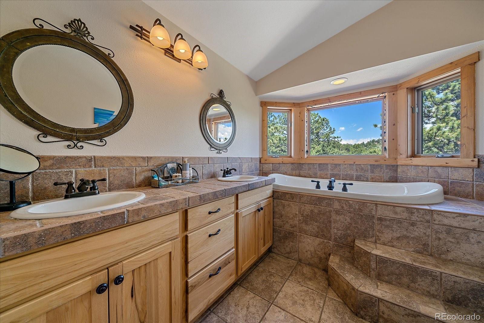 14482 Jubilee Trail Pine, CO 80470 - Photo 34 of 40 a spacious bathroom with a granite countertop double vanity and a large mirror