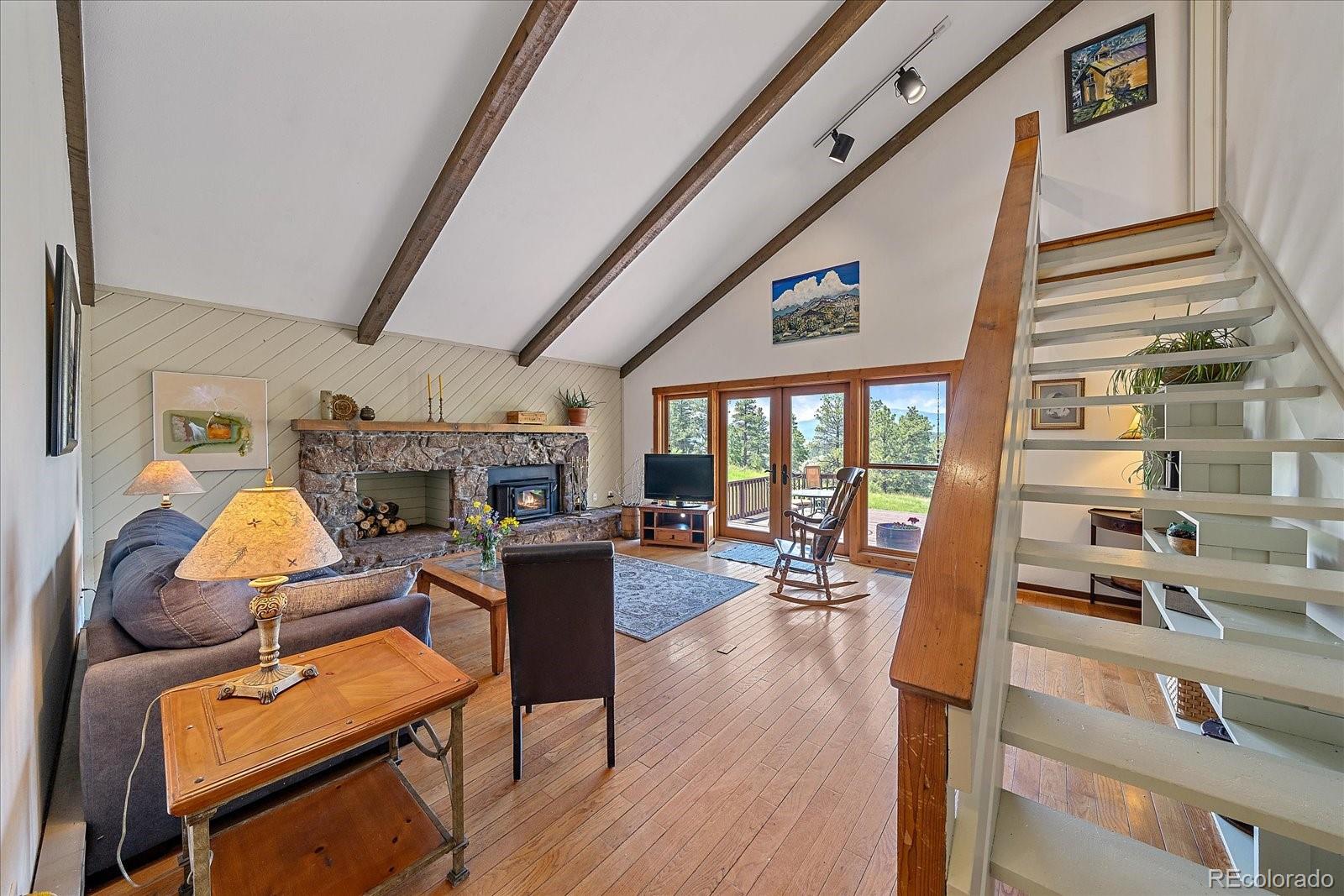 14482 Jubilee Trail Pine, CO 80470 - Photo 9 of 40 a living room with furniture a fireplace and wooden floor