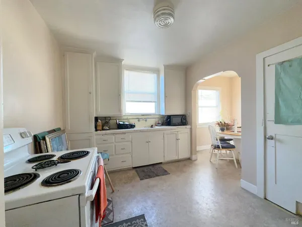 a kitchen that has a lot of white cabinets and wooden floor
