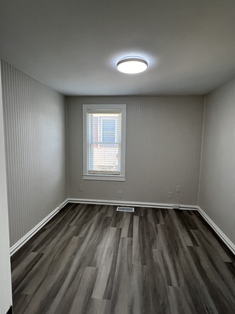 407 Abe Street Plano, IL 60545 - Photo 8 of 15 an empty room with wooden floor and windows