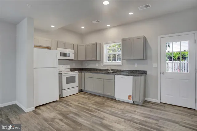 a kitchen with granite countertop a sink stove and refrigerator