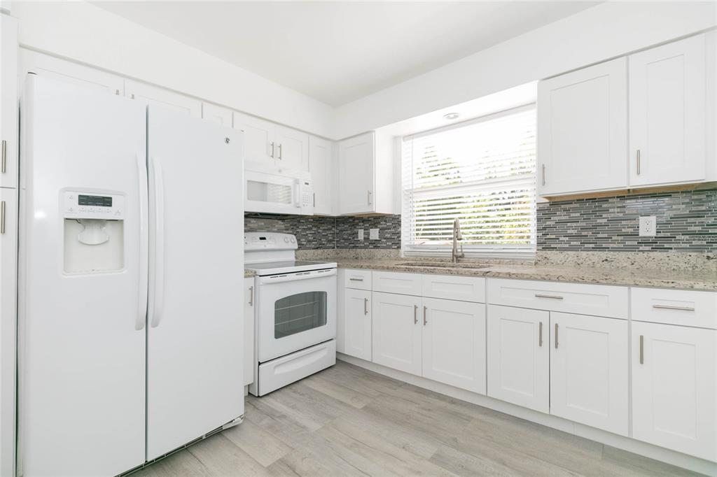 7531 Abonado Road, Unit 1 Tampa, FL 33615 - Photo 9 of 26 a kitchen with granite countertop white cabinets and white appliances