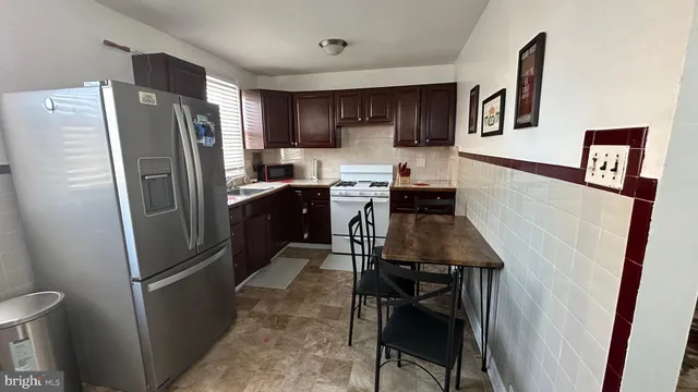 a kitchen with stainless steel appliances a refrigerator a stove a sink a dining table and chairs