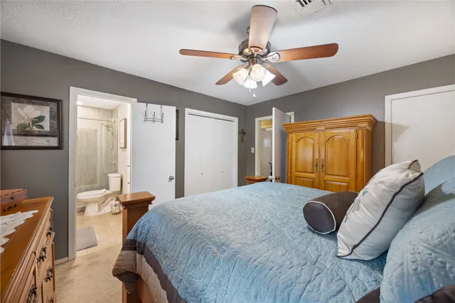 a bedroom with a bed ceiling fan and a wooden floor