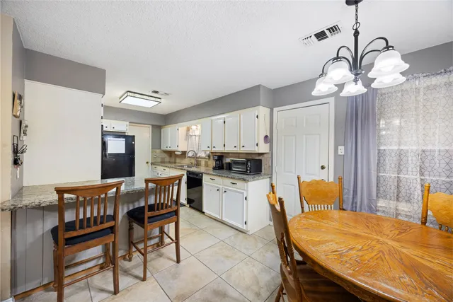 a dining room filled chandelier and kitchen view